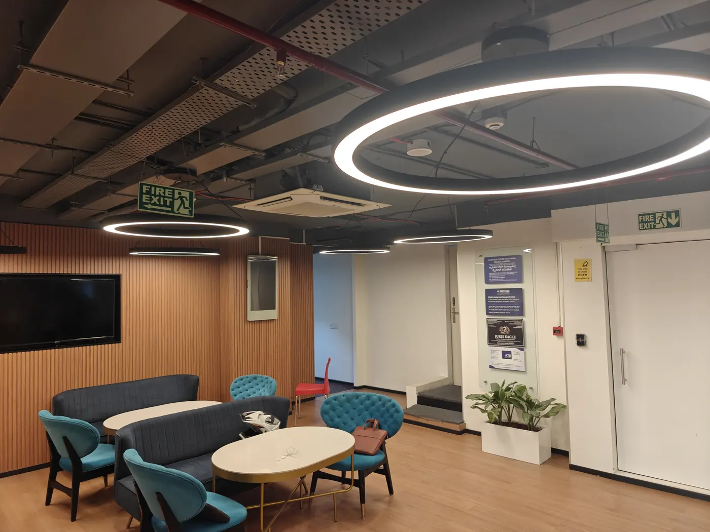A meeting area in the Bengaluru office, with a round table, soft seating and a wall screen.