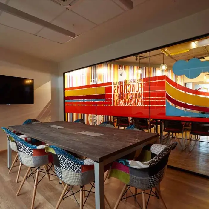 A meeting room in New Delhi, with a long table and a painted wall behind it.