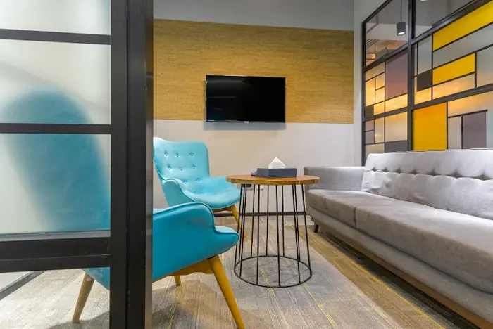 A waiting area in Mumbai, with a sofa, an armchair and a wall screen.